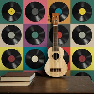 Könnte beinhalten: Eine Holzukulele steht vor einem farbenfrohen Hintergrund aus Schallplatten. Die Schallplatten haben verschiedenfarbige Etiketten und sind auf einem Raster aus Gelb, Türkis, Rosa und anderen Farbtönen angeordnet. Zwei Bücher liegen auf einer Holzoberfläche.
