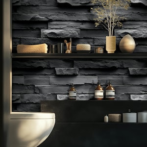May include: A modern bathroom with a dark gray stone wall. Shelves hold a sponge, glass, decorative items, and bottles. A white toilet is in the foreground. The room has a minimalist design with a focus on texture and neutral colors.