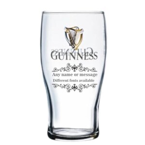 May include: A clear pint glass with the Guinness logo and text. The logo features a harp design. The text on the glass reads "GUINNESS" and "Any name or message, Different fonts available". The glass has a curved shape.