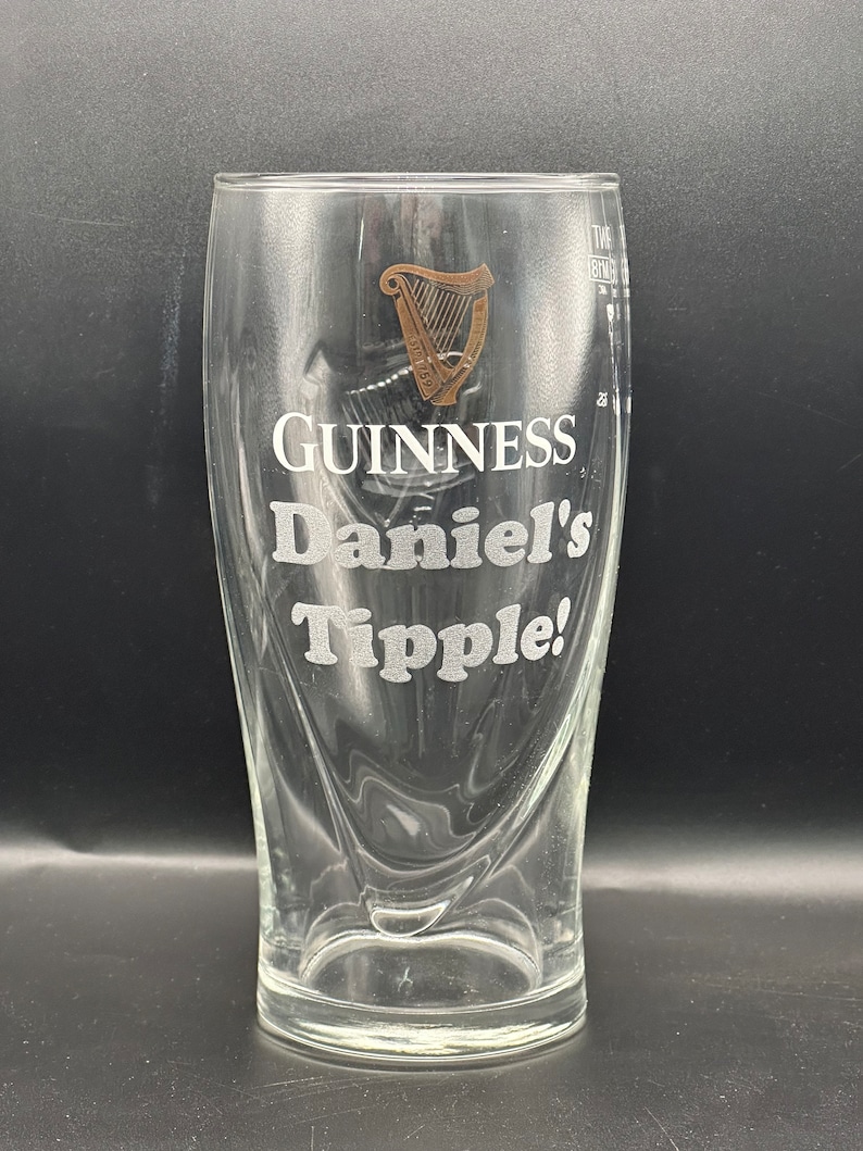 May include: A clear glass pint glass with a Guinness logo and the text "Daniel's Tipple!" etched on the side.
