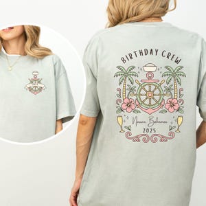 May include: A light green t-shirt with a nautical-themed design. The front features an anchor with the name "Emily". The back displays "BIRTHDAY CREW" above a ship's wheel, palm trees, flowers, and the text "Nassau, Bahamas 2025".