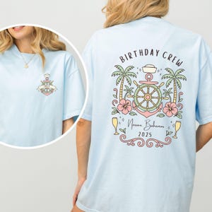 May include: Light blue t-shirt with a nautical-themed design. The front features an anchor with a banner that says "EMILY". The back has the words "BIRTHDAY CREW" above a design with a ship's wheel, palm trees, and the text "Nassau, Bahamas 2025".