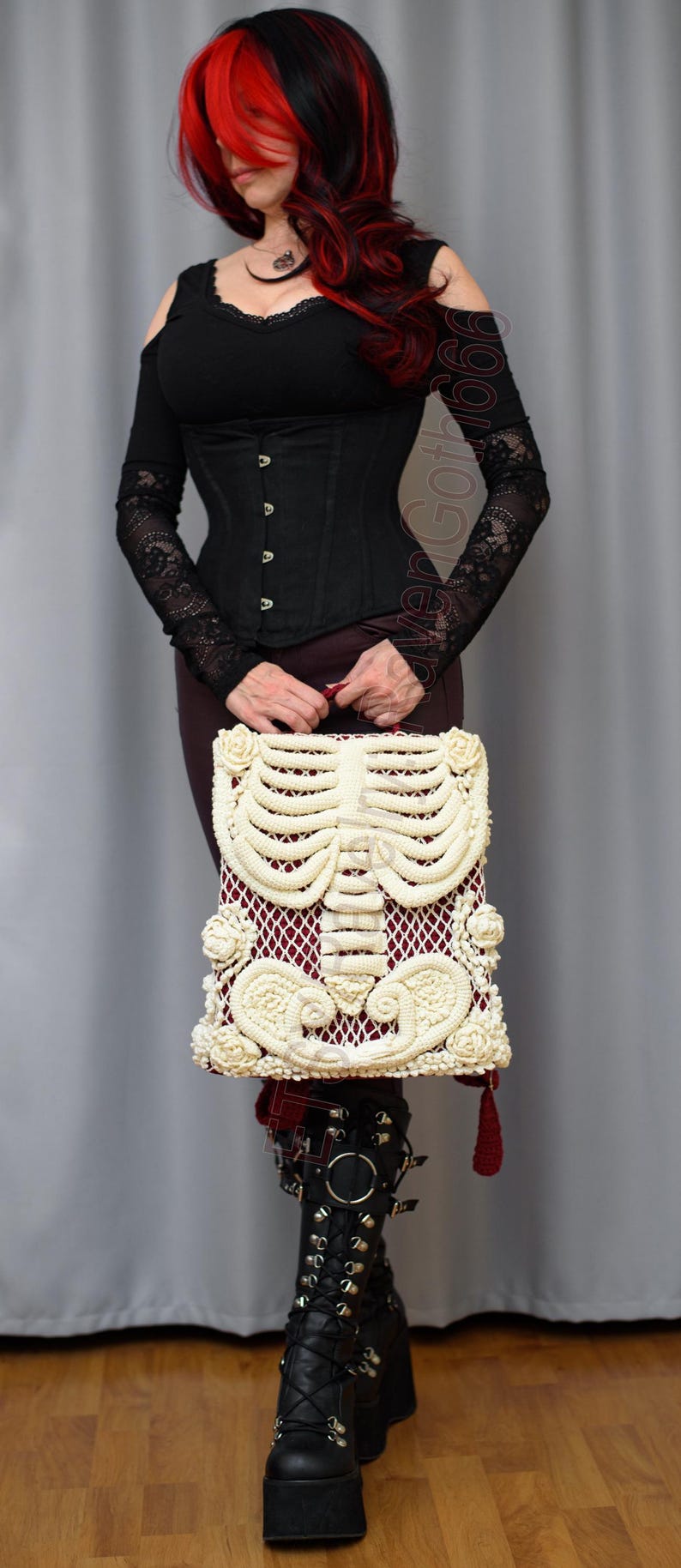 K&ouml;nnte beinhalten: Cremefarbene Makramee-Handtasche mit Skelett-Design und rotem Innenfutter. Die Tasche wird vor einer Person gehalten, die ein schwarzes Korsett, ein lang&auml;rmliges Oberteil und Plateaustiefel tr&auml;gt. Das Thema ist Gothic.
