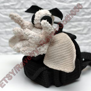 May include: A handmade black and white crochet creature with outstretched arms. The creature has a black body, head, and ears, with off-white arms and face. The image includes the text "ETSY/RavenGoth666".