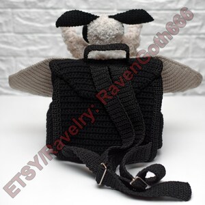 May include: A black crochet backpack with adjustable straps and a top handle. The backpack features a plush, light-coloured head with black ears and grey wings. The text "ETSY/Ravelry: Ravencoth666" is visible.