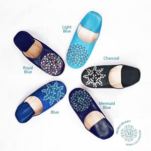 May include: Five pairs of leather slippers with different colored leather and jeweled embellishments. The colors are light blue, royal blue, blue, mermaid blue, and charcoal.