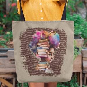 Puede incluir: Una bolsa de lona marrón con una correa negra. La bolsa presenta una ilustración colorida de una mujer con una pila de libros en la cabeza. El texto "POWER MY VOICE MY PRIDE MY FUTURE MY DREAM" se repite alrededor de la ilustración.