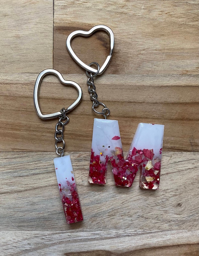 Top view of a customizable Resin Initial Keychain made with white smokey epoxy resin, in which red and gold flakes are inserted to give it a stylish look.