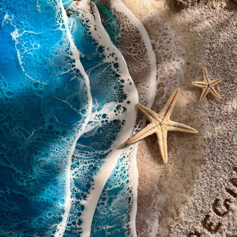 Closeup view of beautiful ocean beach resin wall art resting on a wooden base with customizable names or messages on the sand.