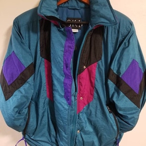 May include: A teal blue ski jacket with black, purple, and pink color blocking. The jacket has a zipper closure and a drawstring at the waist.