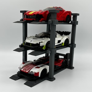 May include: A three-tiered black display stand holding three toy race cars. The cars are red, white, and black. The top car is red with a yellow stripe. The middle car is white with green accents. The bottom car is red and white.