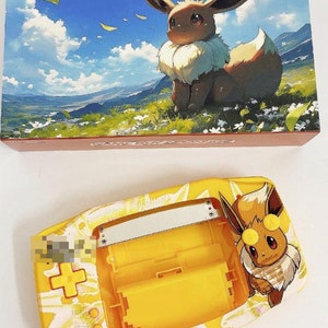 May include: A yellow Game Boy Advance SP with a custom design featuring Eevee, a Pokemon character. The design includes a white background with a yellow starburst pattern. The Game Boy Advance SP is open, revealing the yellow cartridge slot and silver screen.