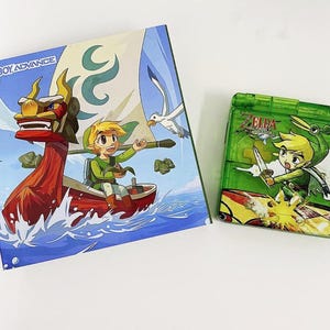 May include: A green Game Boy Advance SP video game cartridge with a cartoon image of Link from the Legend of Zelda: The Wind Waker game. The cartridge is in a clear plastic case with a green background. The image shows Link holding a sword and standing on a boat.