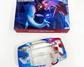 May include: A clear Game Boy Advance SP shell with a blue and red Pokemon design featuring the text "Pokemon" and a stylized image of two Pokemon. The shell is open and the internal components are visible.