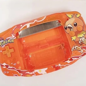 May include: Orange and white Game Boy Advance SP with a Pokemon design. The design features a cartoon bird with the word "Pokemon" printed on the front.