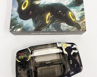 May include: A clear plastic Game Boy Advance SP with a black and white design featuring a Pokemon character. The design includes a black and white image of a Pokemon character with yellow accents. The Game Boy Advance SP is a handheld video game console.