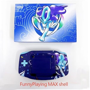 Op de afbeelding: Een blauwe en paarse handheld gameconsole met bijpassende doos. De console heeft een karakterontwerp en een blauw kruisvormig D-pad. De doos heeft het woord "GAME" en een karakterillustratie.