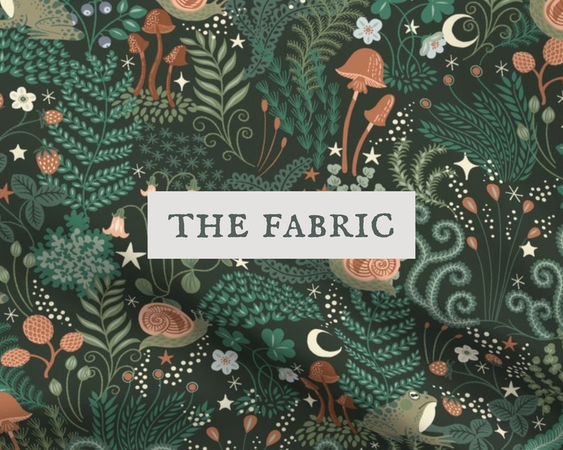 Op de afbeelding: Een donkergroene stof met een herhalend patroon van bruine paddenstoelen, slakken, kikkers, aardbeien, varens en kleine witte sterren en maansikkels. Een wit rechthoekig label met de tekst THE FABRIC is in het midden van de afbeelding geplaatst.