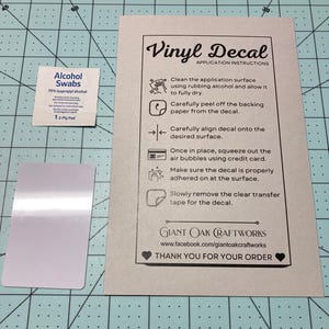 May include: Instructions for applying a vinyl decal. The instructions include cleaning the surface, peeling off the backing paper, aligning the decal, squeezing out air bubbles, and removing the transfer tape. The instructions also include a small package of alcohol swabs.