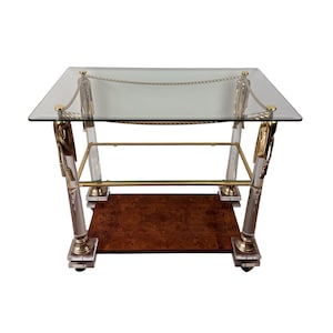 May include: A rectangular side table featuring a clear glass top, four clear acrylic columns with gold-toned metal accents, and decorative gold-toned rope detailing. The base consists of a lower shelf with a brown burl wood veneer finish.