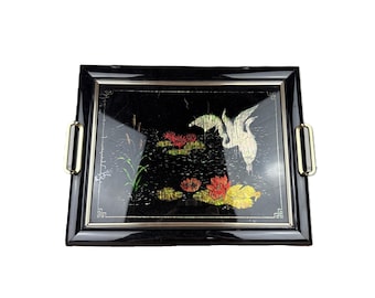 May include: A rectangular black serving tray featuring a glossy finish and gold-toned metal handles on the sides. The center displays a detailed illustration of a white crane in flight over a pond with red and yellow water lilies and green reeds.