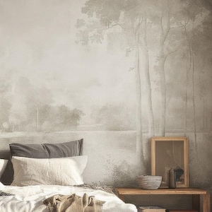 May include: A bedroom featuring a low-profile bed with white and grey bedding, positioned against a wall mural depicting a forest landscape in muted tones. Two wooden side tables flank the bed, with a hanging pendant light and a large window.