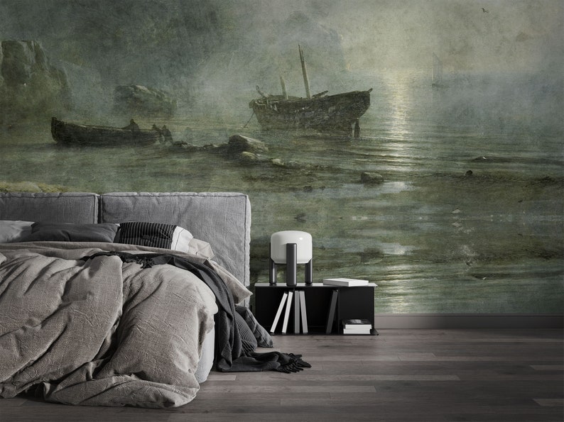 May include: A wall mural featuring a dark, moody seascape with two weathered wooden boats anchored in shallow, rocky water under a hazy, moonlit sky. The scene is rendered in muted shades of green, gray, and brown, creating a textured, atmospheric effect.