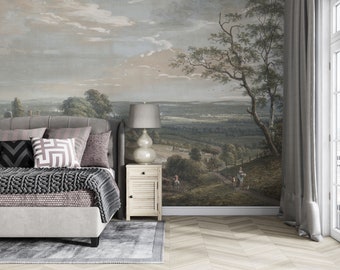 May include: A wall mural featuring a landscape painting with rolling hills, trees, and figures on a path, displayed behind a gray upholstered bed with a gray and white patterned pillow, a light wood nightstand, and a gray table lamp.
