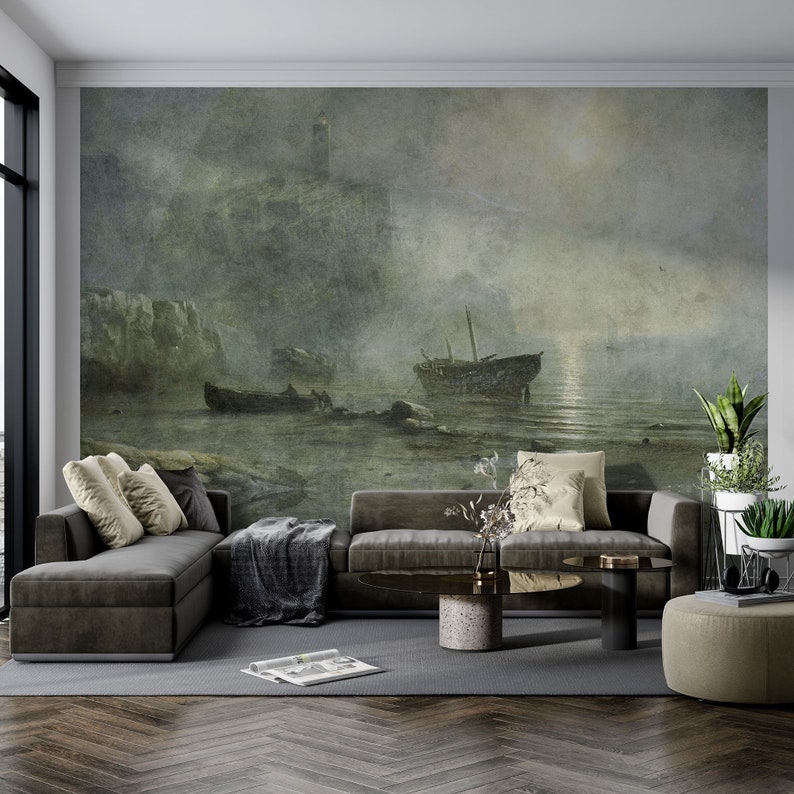May include: A large wall mural featuring a moody, atmospheric seascape painting with a lighthouse on a cliff, two small boats in the water, and a soft, hazy light. The scene is rendered in muted tones of gray, green, and brown, creating a calm, expansive view.