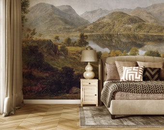 May include: A bedroom with a large landscape mural on the wall. The mural features a lake, mountains, and trees. A bed with a beige headboard and a brown knitted blanket is in the foreground. A lamp sits on a nightstand next to the bed.