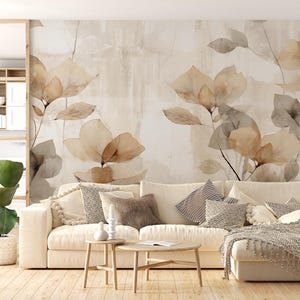 Peut inclure: Une grande fresque murale présentant un imprimé botanique de style aquarelle avec des motifs floraux dans des tons doux de beige, de brun et de gris. La fresque est exposée derrière un canapé d'angle crème avec divers coussins texturés.