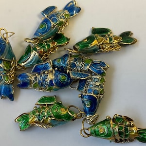 May include: A group of nine blue and green enamel fish charms with gold accents. The charms are linked together with a gold chain.
