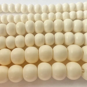 May include: A collection of white round beads of varying sizes. The beads are made of natural materials and have a smooth, polished finish.