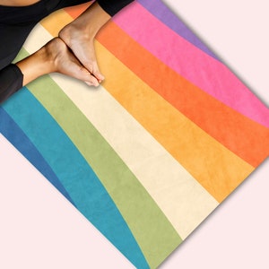 May include: A rainbow yoga mat with a vintage design. The mat has stripes of purple, pink, orange, yellow, green, blue, and white.