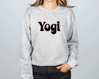 Może przedstawiać: Szara bluza z nadrukiem słowa "Yogi" w kolorze czarnym z różowym obramowaniem.