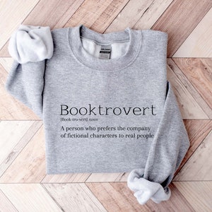 May include: Gray sweatshirt with the text "Booktrovert [Book-tro-vert] noun A person who prefers the company of fictional characters to real people" printed on the front.
