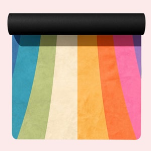 May include: A rolled up yoga mat with a rainbow design. The mat has stripes of blue, green, cream, yellow, orange, pink, and purple.