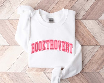 May include: White sweatshirt with the text "BOOKTROVERT" in pink letters with a white outline.