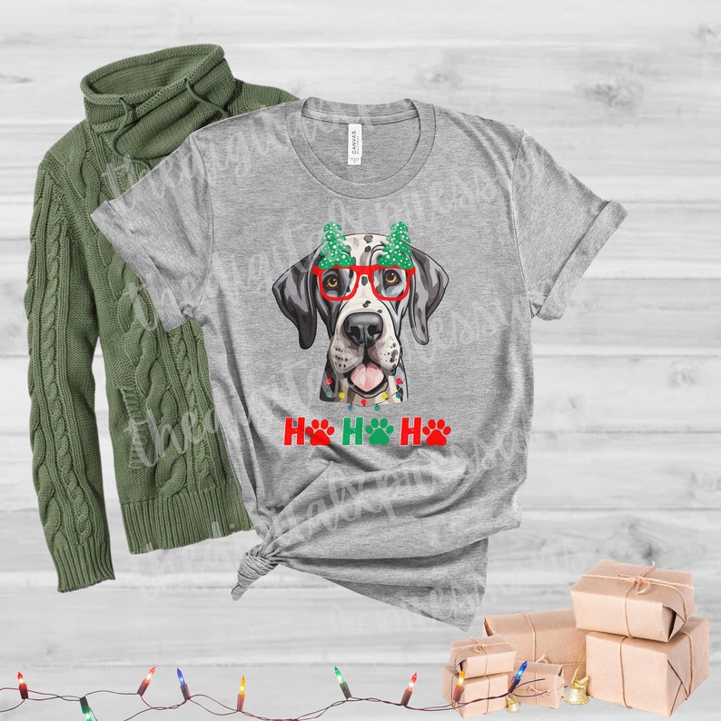 May include: A gray t-shirt with a cartoon image of a Dalmatian dog wearing Christmas lights and glasses with a Christmas tree design. The text "Ho Ho Ho" is below the dog with paw prints for the Os.