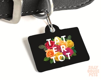 Könnte beinhalten: Schwarzer Hundeanhänger mit dem Text "TATERTOT" in weißen Buchstaben und einem farbenfrohen Blumenarrangement aus roten, orangen und gelben Rosen. Der Anhänger ist an einem schwarzen Lederhalsband befestigt.