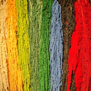 May include: A collection of dried flower stems in various colors, including white, yellow, green, blue, black, and red. The stems are arranged vertically and are all approximately the same length.