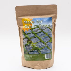 May include: A brown paper bag with a label that reads "Moss for Sunny Areas." The label features a picture of moss growing on stone. Text on the label says "Grow Moss in Sun or Shade... Just Add Water" and "Covers up to 15 square feet."