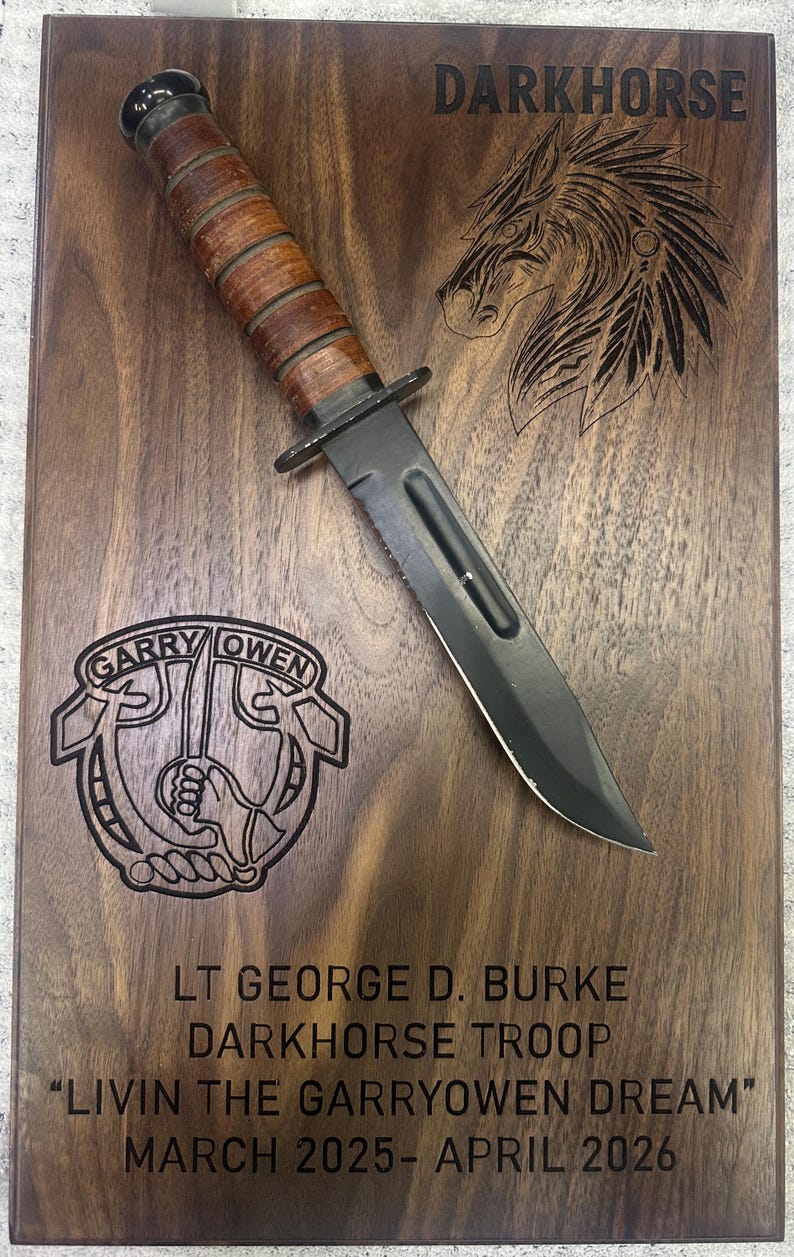 May include: A wooden plaque with a military-style knife and etched text. The plaque features the word "DARKHORSE" and a horse head design. Etched text includes "GARRY OWEN", "LT GEORGE D. BURKE", and "LIVIN THE GARRYOWEN DREAM".