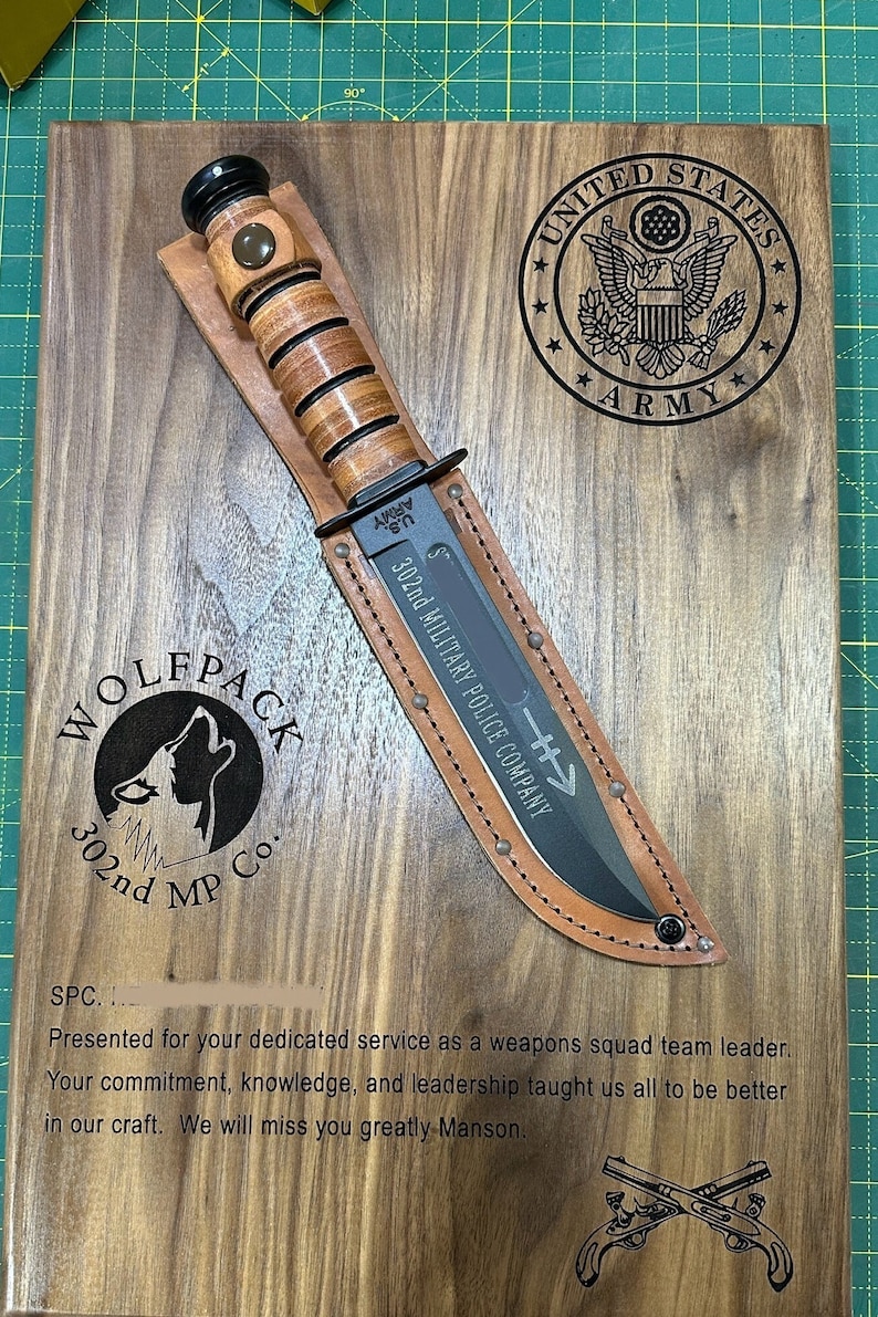 May include: A wooden plaque with a knife and leather sheath. The plaque features the US Army emblem, the words "302nd MILITARY POLICE COMPANY", and the "WOLFPACK" logo. The plaque also has an inscription.