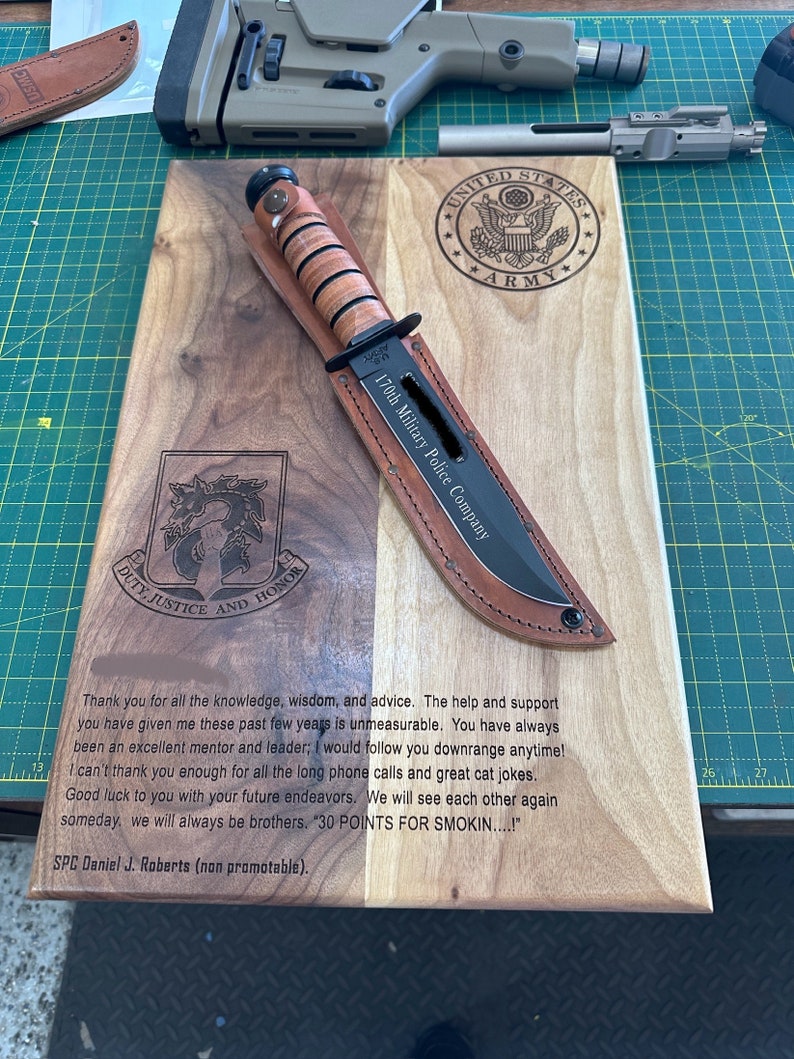 May include: A wooden plaque with a knife and sheath, featuring the text "170th Military Police Company" and the U.S. Army emblem. The plaque also includes a message and the text "DUTY, JUSTICE AND HONOR."