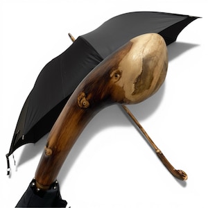 May include: A black umbrella with a distinctive wooden handle. The handle is crafted from wood, featuring a natural, organic form with light and dark brown tones. The umbrella's canopy is black.