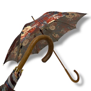 May include: An open umbrella with a curved wooden handle and a floral and plaid patterned canopy. The canopy features a mix of red, cream, and brown floral designs over a plaid background. The handle is a light brown colour.