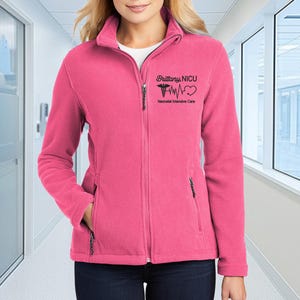 a woman in a pink jacket standing in a hallway