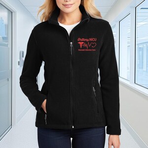 a woman standing in a hallway wearing a black jacket