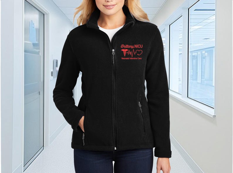 a woman standing in a hallway wearing a black jacket